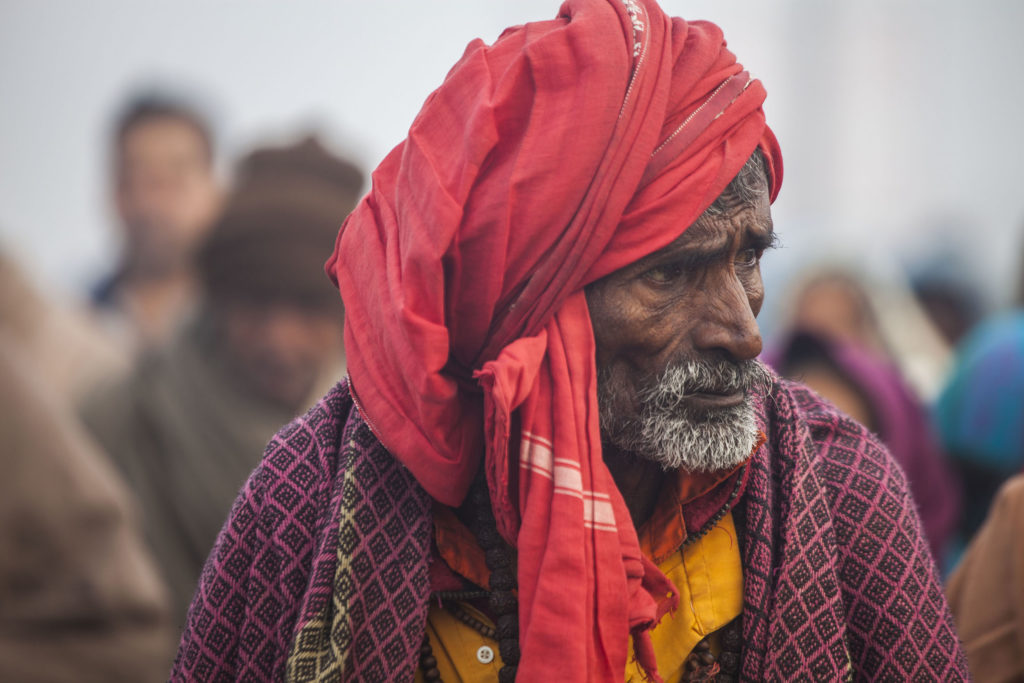 An elderly Indian man wearing a red turban walking to the Ganges at Marg Melah in Allahabad India