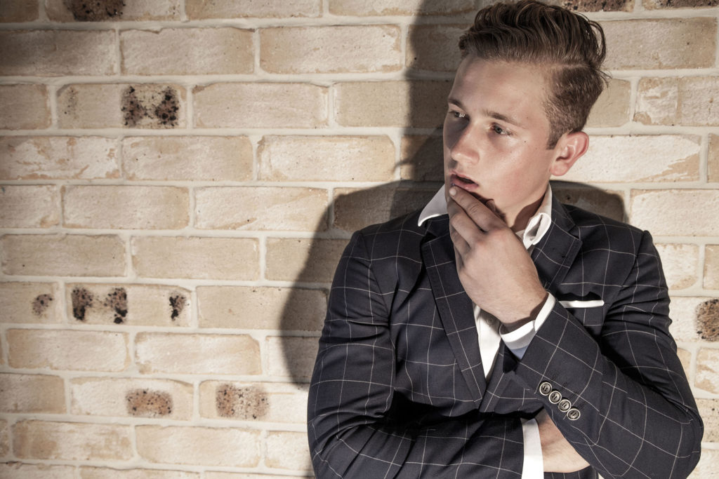 Jesse against a brick wall wearing a suit